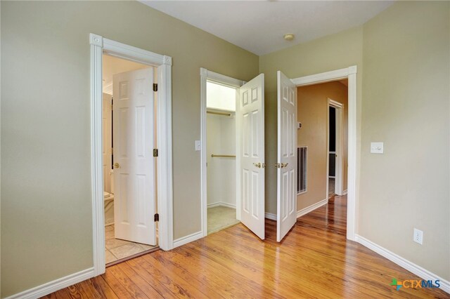 unfurnished bedroom featuring light hardwood / wood-style floors and ensuite bathroom