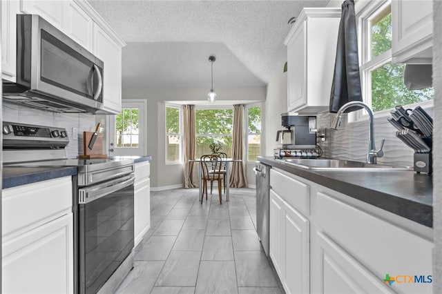 2804 Bluejay Dr, Killeen, TX 76549 - kitchen featuring stainless steel appliances, a sink, dark countertops, backsplash, and a textured ceiling