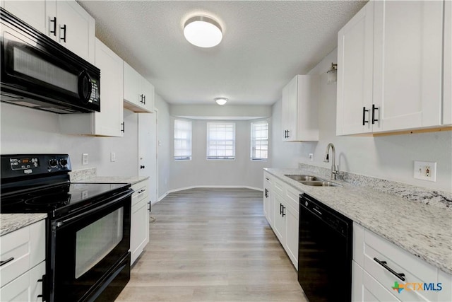 kitchen with a textured ceiling, black appliances, light wood-style flooring, and a sink