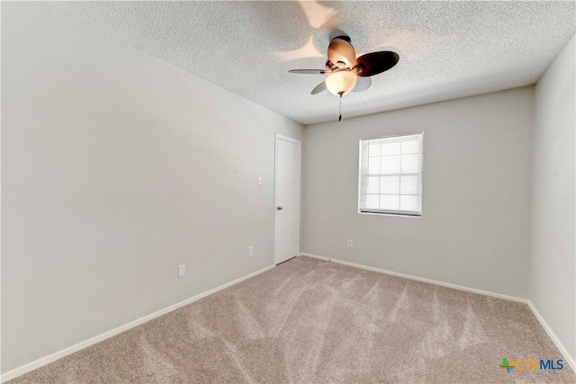 empty room featuring baseboards, light carpet, a textured ceiling, and ceiling fan