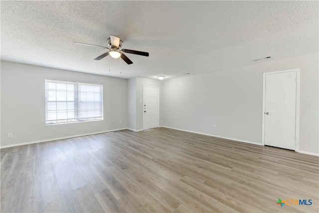 spare room featuring visible vents, a textured ceiling, a ceiling fan, and wood finished floors