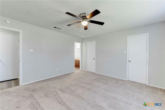 carpeted spare room featuring visible vents, baseboards, a textured ceiling, and ceiling fan