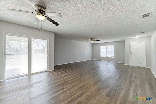 unfurnished living room featuring visible vents, baseboards, wood finished floors, a textured ceiling, and a ceiling fan