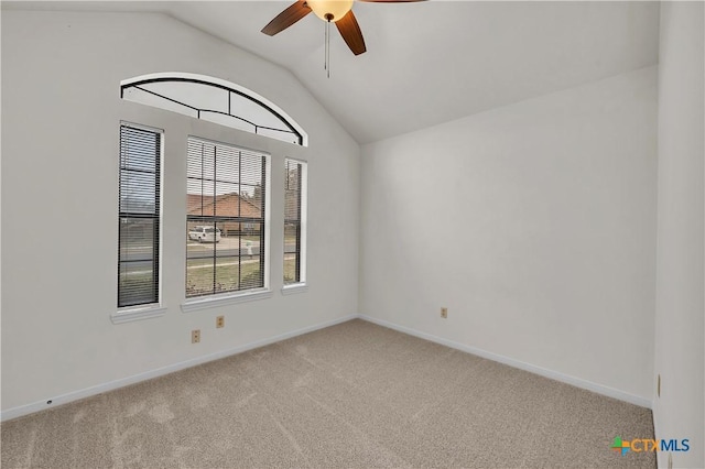 spare room featuring a ceiling fan, a wealth of natural light, light colored carpet, and vaulted ceiling