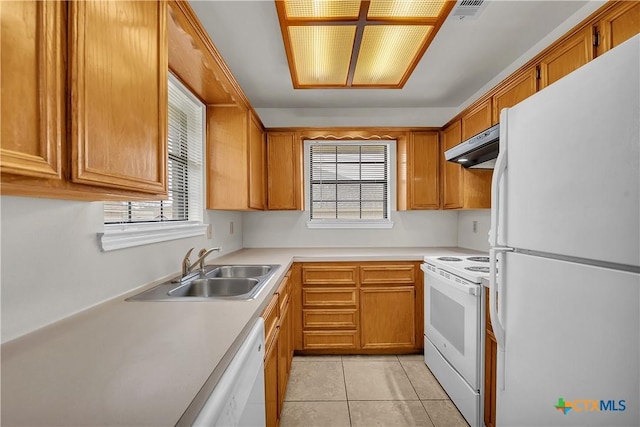 kitchen with brown cabinets, white appliances, light countertops, and a sink