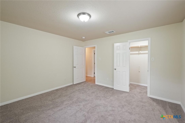 503 Pine St, Smithville, TX 78957 - unfurnished bedroom with a walk in closet, carpet flooring, and a textured ceiling