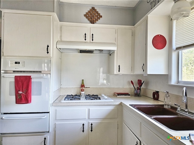 kitchen with white appliances, sink, and white cabinets