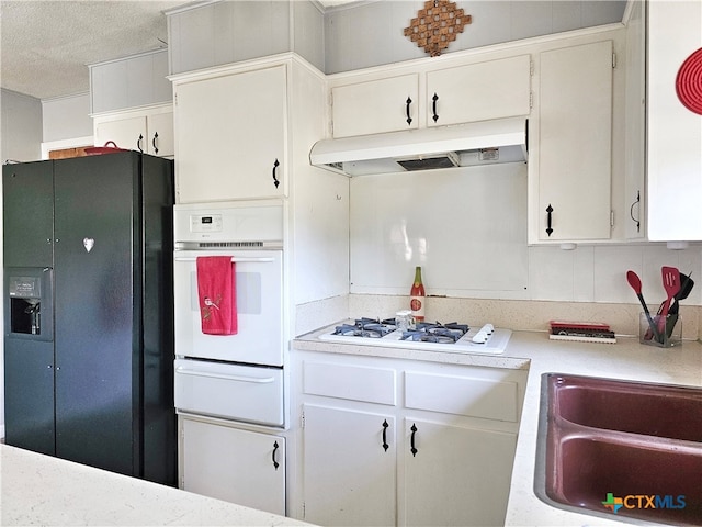 kitchen featuring backsplash, a textured ceiling, sink, white cabinets, and white appliances