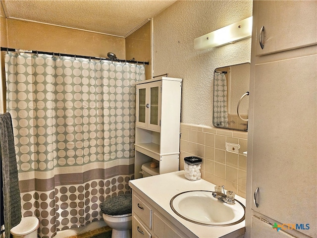 bathroom featuring toilet, vanity, tile walls, and a textured ceiling