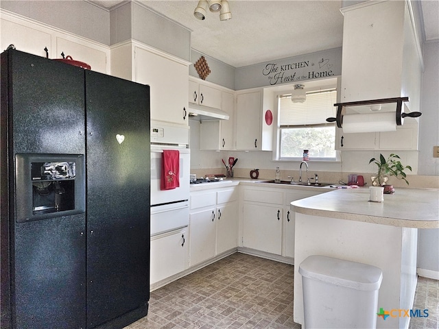 kitchen with black fridge, white oven, white cabinetry, sink, and stainless steel gas cooktop