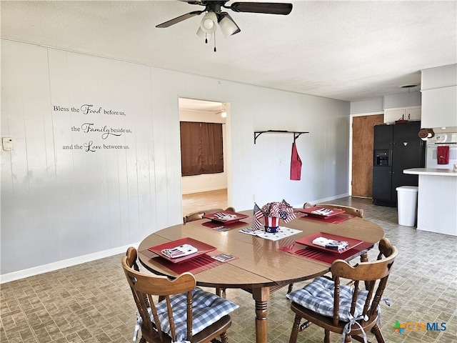 dining space with wood walls, ceiling fan, and a textured ceiling