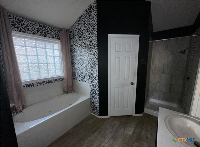 bathroom featuring vaulted ceiling, hardwood / wood-style floors, vanity, separate shower and tub, and a textured ceiling