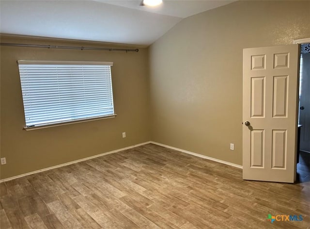 empty room featuring hardwood / wood-style flooring and vaulted ceiling