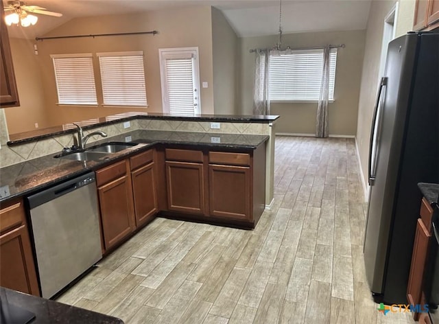 kitchen featuring sink, vaulted ceiling, hanging light fixtures, appliances with stainless steel finishes, and kitchen peninsula