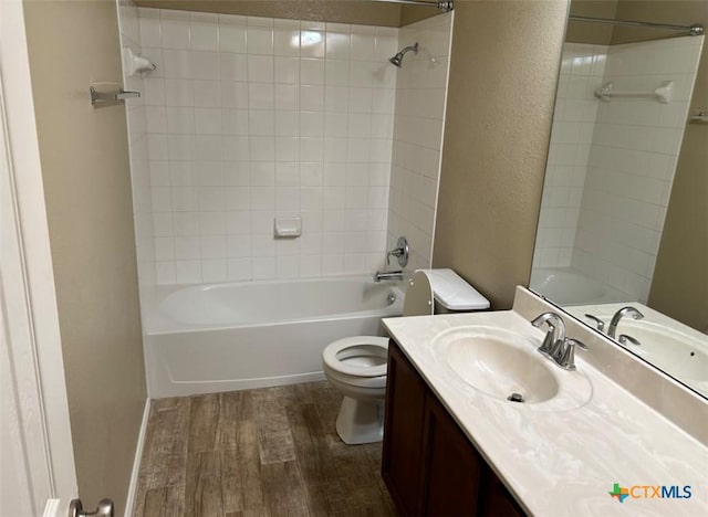 full bathroom featuring vanity, tiled shower / bath combo, wood-type flooring, and toilet