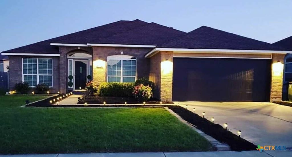 single story home with a garage and a front lawn