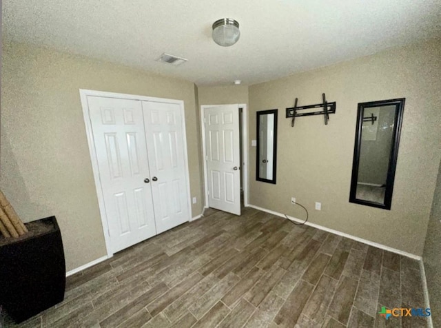 unfurnished bedroom with dark hardwood / wood-style floors and a closet