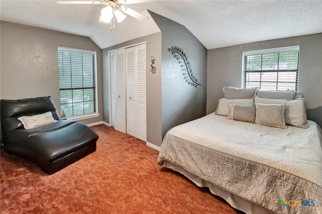 carpeted bedroom with a textured ceiling, lofted ceiling, ceiling fan, and a closet