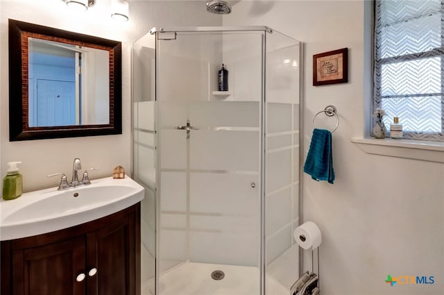 bathroom with a shower with shower door and vanity