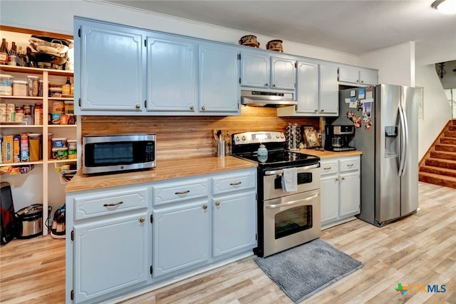 kitchen with blue cabinetry, stainless steel appliances, and light hardwood / wood-style flooring