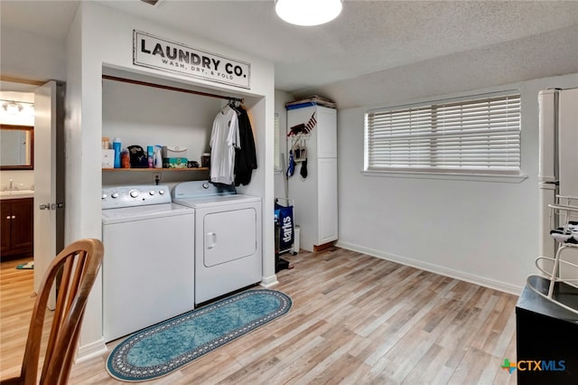 laundry room with sink, a textured ceiling, washer and dryer, and light hardwood / wood-style flooring