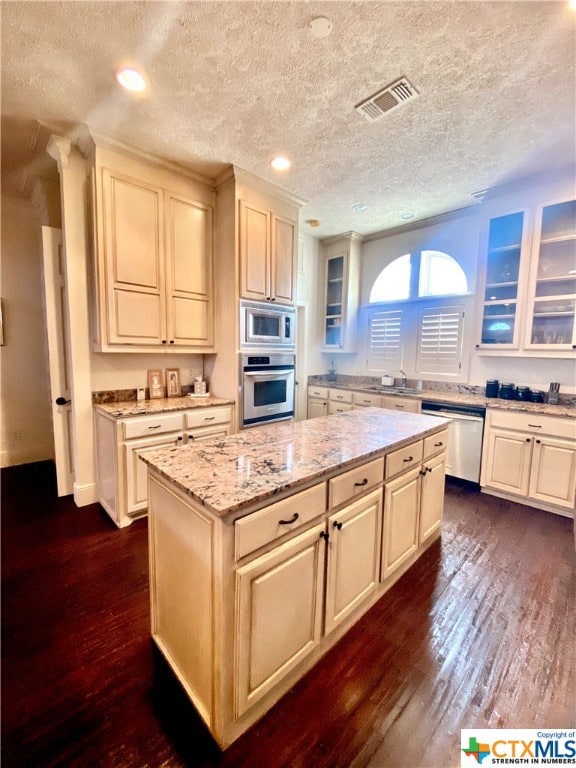 kitchen with stainless steel appliances, dark wood-type flooring, a textured ceiling, and a center island