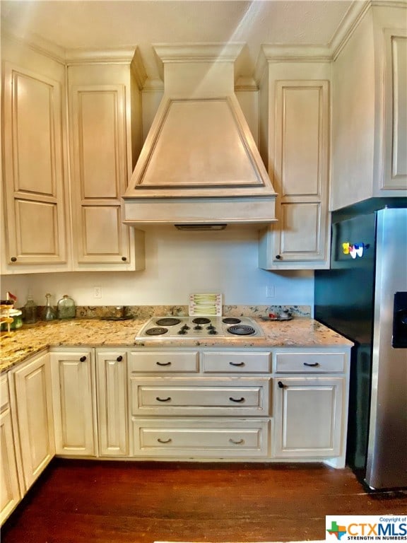 kitchen with stainless steel refrigerator with ice dispenser, custom range hood, dark hardwood / wood-style floors, white electric stovetop, and cream cabinetry