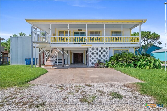 raised beach house featuring driveway, stairway, a front lawn, a porch, and a carport