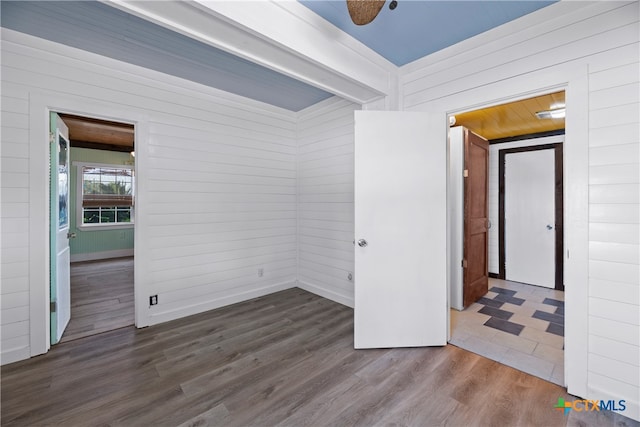 unfurnished room with wood walls, hardwood / wood-style flooring, and ceiling fan