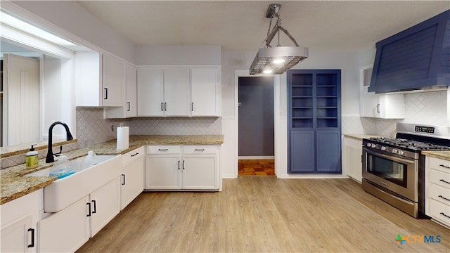 4610 Camellia St, Victoria, TX 77904 - kitchen with stainless steel range with gas cooktop, wall chimney exhaust hood, decorative backsplash, and white cabinets