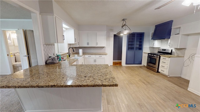 4610 Camellia St, Victoria, TX 77904 - kitchen featuring stainless steel gas range, extractor fan, a peninsula, light stone countertops, and backsplash