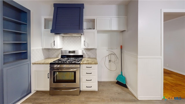 4610 Camellia St, Victoria, TX 77904 - kitchen featuring stainless steel gas stove, wall chimney range hood, open shelves, light stone countertops, and white cabinets