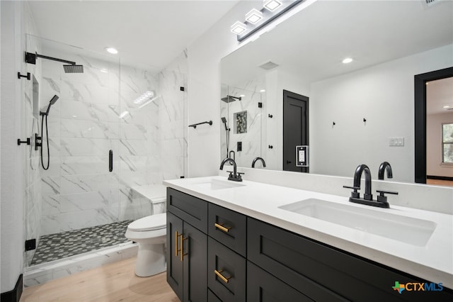 bathroom featuring vanity, wood-type flooring, a shower with shower door, and toilet