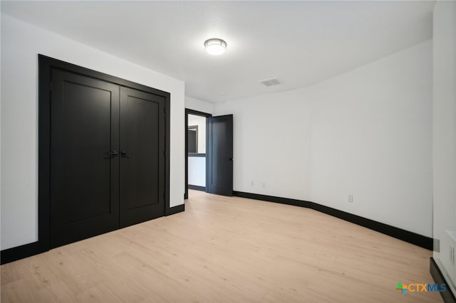 unfurnished bedroom featuring light hardwood / wood-style floors and a closet