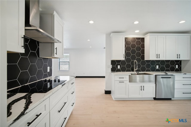 kitchen with white cabinets, light hardwood / wood-style floors, wall chimney range hood, and tasteful backsplash