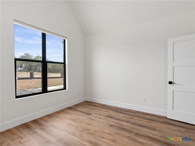 unfurnished room with lofted ceiling, light wood-style flooring, and baseboards