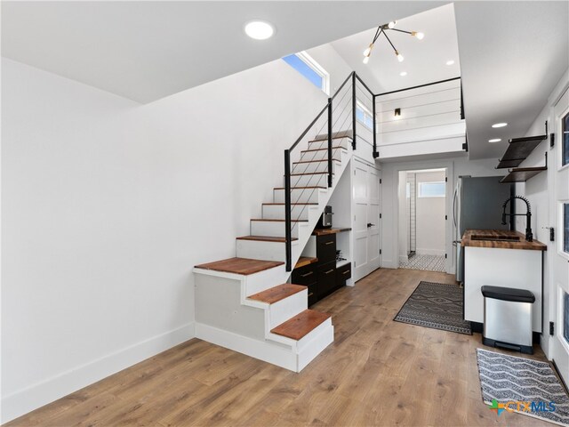 stairway featuring wood finished floors, baseboards, recessed lighting, and a notable chandelier