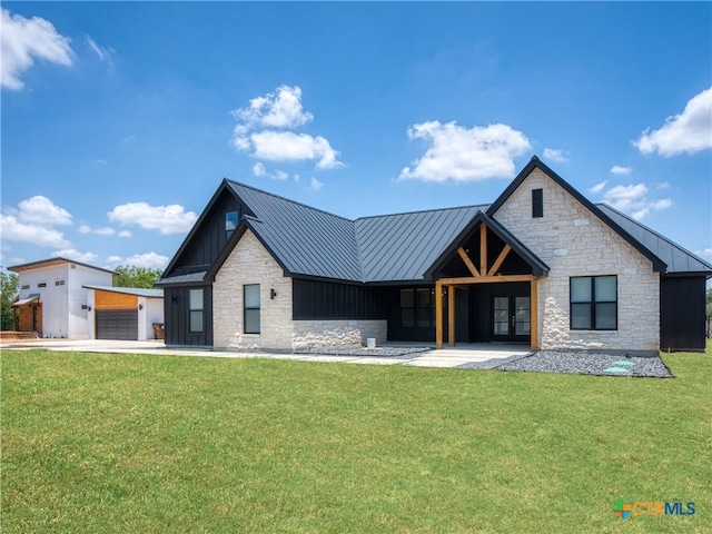 modern farmhouse style home featuring a standing seam roof, stone siding, metal roof, board and batten siding, and a front yard