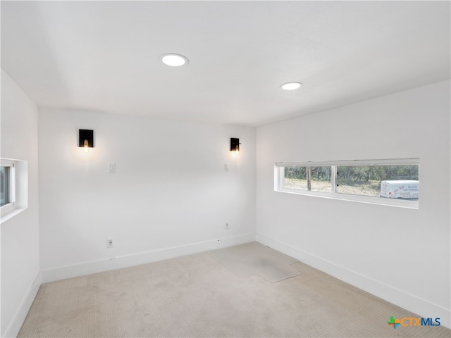 unfurnished room featuring light carpet and baseboards