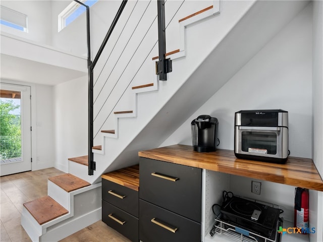 bar featuring plenty of natural light, light wood-style flooring, and stairs