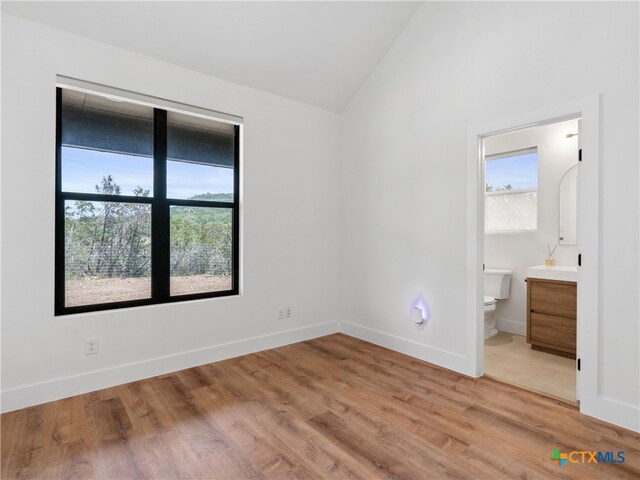 unfurnished bedroom with light wood finished floors, vaulted ceiling, baseboards, and multiple windows