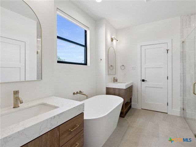 bathroom featuring a shower stall, tile patterned floors, a sink, a soaking tub, and two vanities