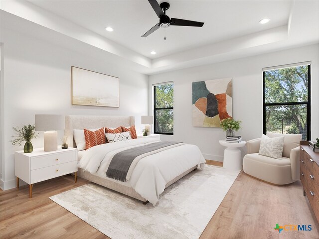 bedroom with recessed lighting, a raised ceiling, light wood finished floors, and baseboards