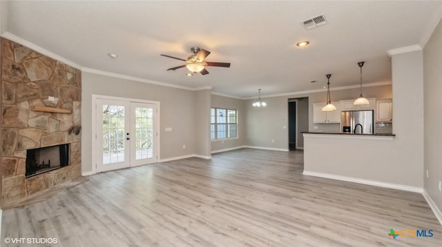 1974 Canyon Bnd, Canyon Lake, TX 78133 - unfurnished living room featuring a ceiling fan, wood finished floors, a fireplace, baseboards, and a chandelier