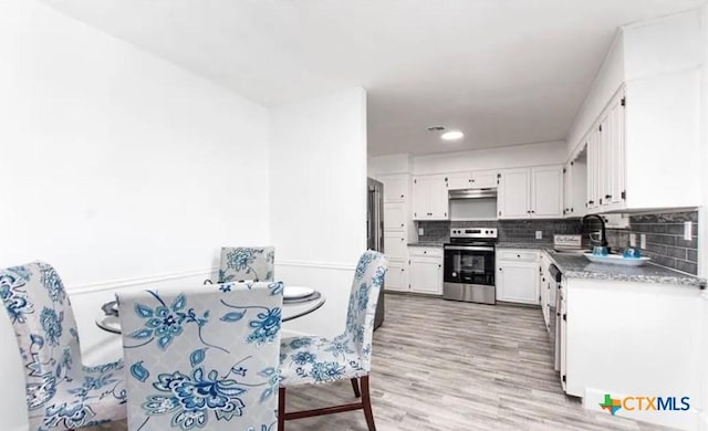 902 Concord Dr, Temple, TX 76504 - kitchen featuring stainless steel range oven, white cabinets, light wood-style floors, decorative backsplash, and under cabinet range hood