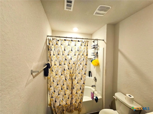 bathroom with shower / bath combination with curtain, a textured ceiling, and toilet