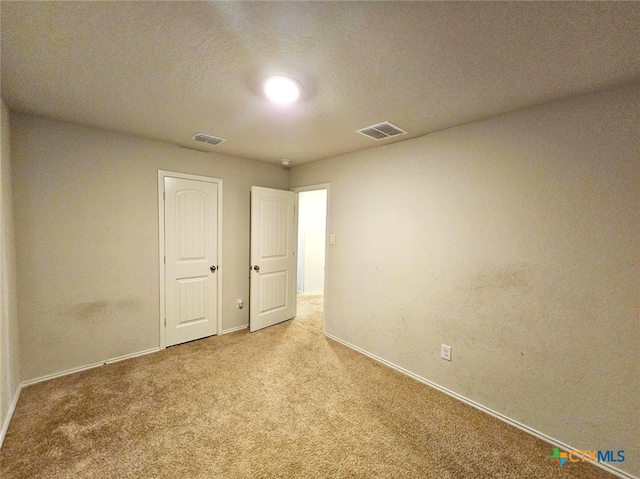 unfurnished room with carpet flooring and a textured ceiling