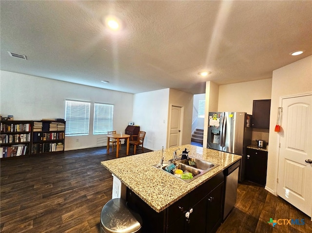 kitchen with an island with sink, stainless steel dishwasher, dark wood-type flooring, and sink