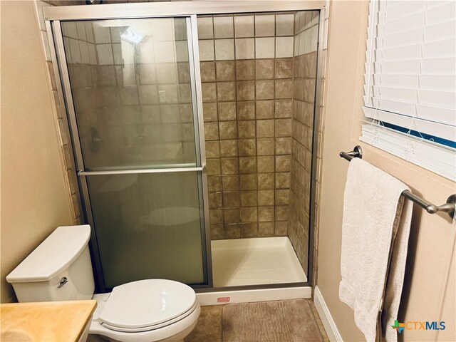 bathroom featuring vanity, a shower with shower door, tile patterned floors, and toilet