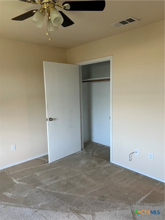 unfurnished bedroom with a closet, carpet flooring, and ceiling fan